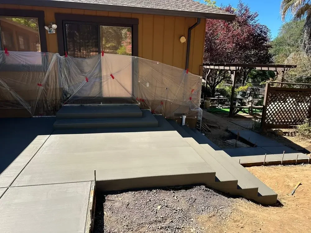 Wide concrete entry steps and landings beside a wood-sided home